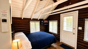 A bedroom with a bed, a ceiling fan, a thermostat, and a door.