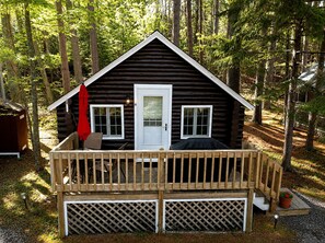 A cabin with a deck, a door, and windows. - Cabin 4 (Lincolnville)