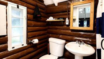 Baño rústico y compacto con tocador, inodoro y espejo.