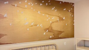Una camera da letto con un letto, una ventola a soffitto e un murale raffigurante uccelli.