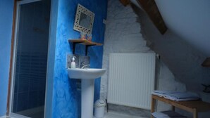 Un baño con lavamanos blanco, paredes azules, un radiador y un pequeño estante con artículos de aseo.