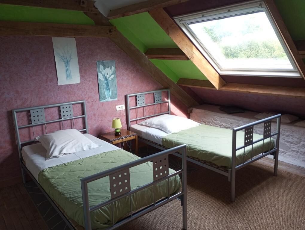 A dormitory room with two metal bunk beds, a skylight, and artwork on the walls.