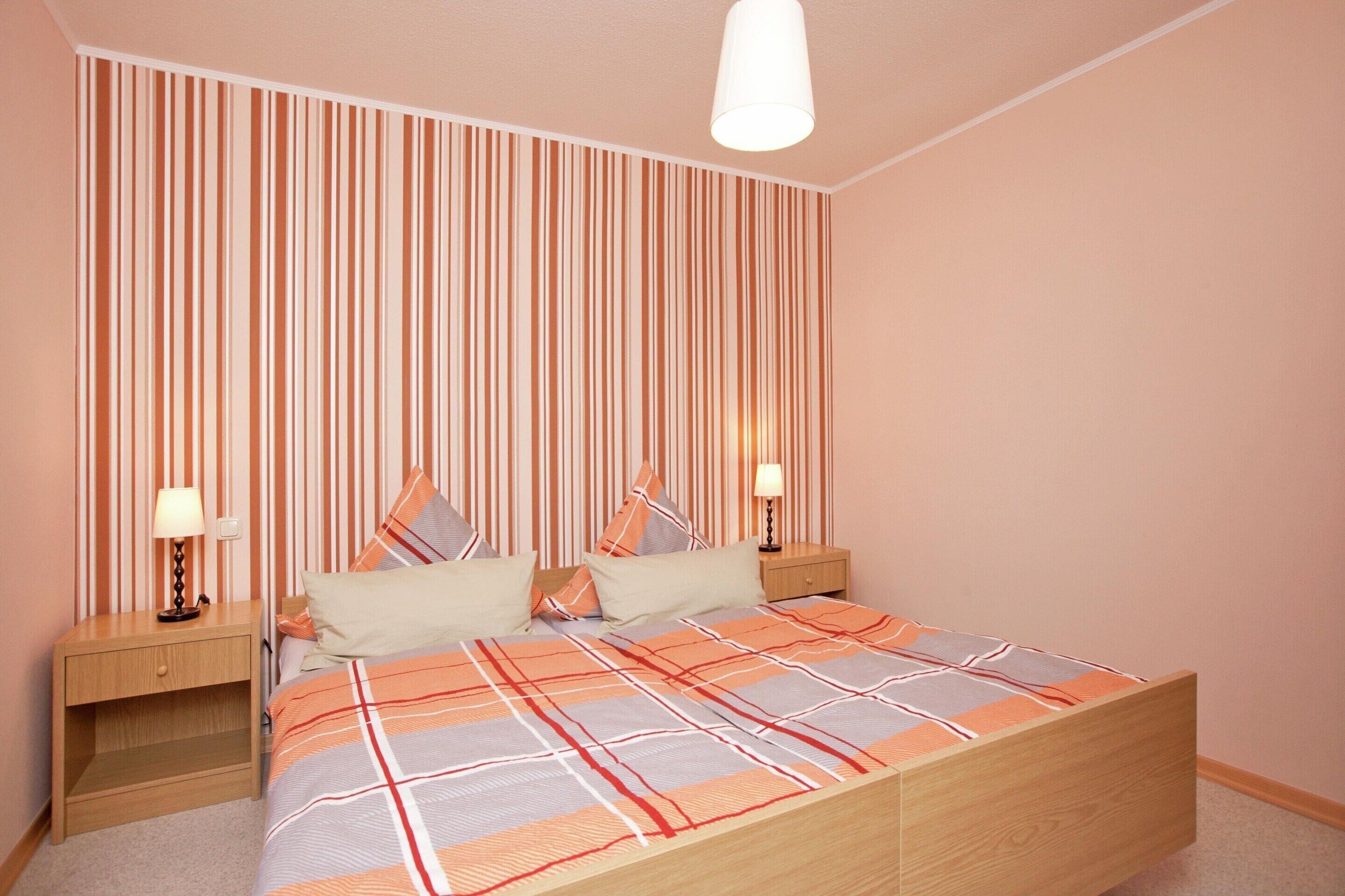 Ein Schlafzimmer mit einem Bett, zwei Nachttischen und einer Wand mit vertikalen Streifen.