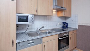 Une cuisine équipée de meubles en bois, d’un four à micro-ondes, d’un évier, d’une machine à café et d’un four.
