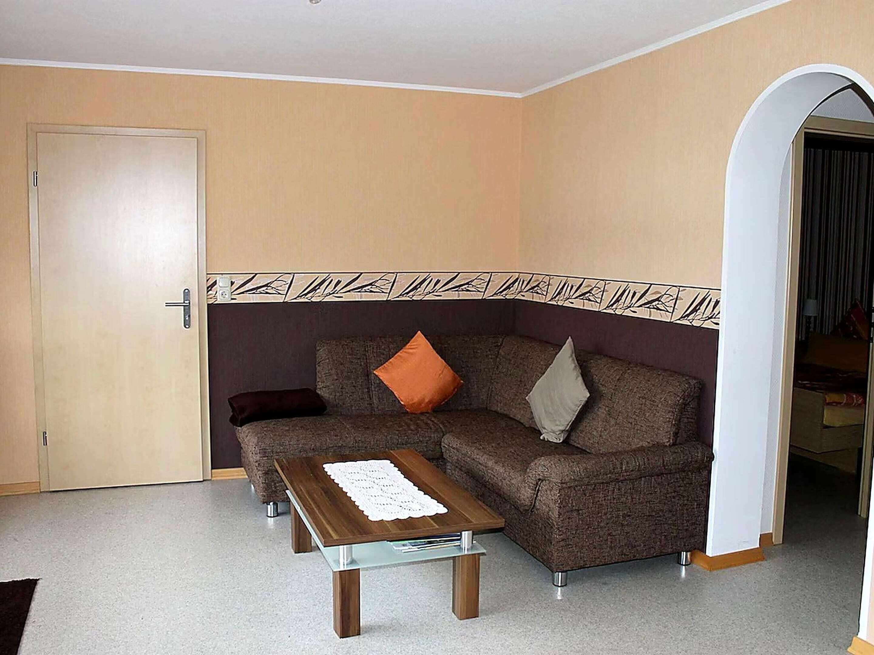 Un salon avec un canapé, une table basse et une bordure décorative sur le mur.