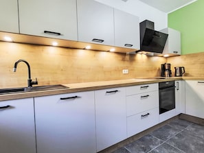 Eine moderne Küche mit weißen Schränken, einer Edelstahl-Spüle und einem eingebauten Backofen.