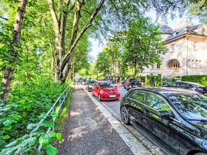 Eine von Bäumen gesäumte Straße mit parkenden Autos und einem Gebäude mit einer Kuppel.