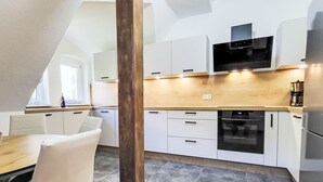Una cocina moderna con armarios blancos, encimera de madera y horno integrado.