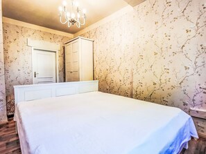 Ein Schlafzimmer mit einem großen Bett, einem Kleiderschrank, einem Spiegel und einer Chandelier.
