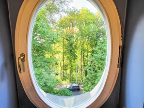 Ein Fenster mit Blick auf eine bewaldete Landschaft und einen Parkplatz.