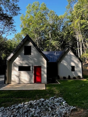 A two-story wooden building with a red door, surrounded by trees. - Cozy and Secluded Cottage in the Woods of Western North Carolina, near Pisgah National Forest (Balsam Grove)