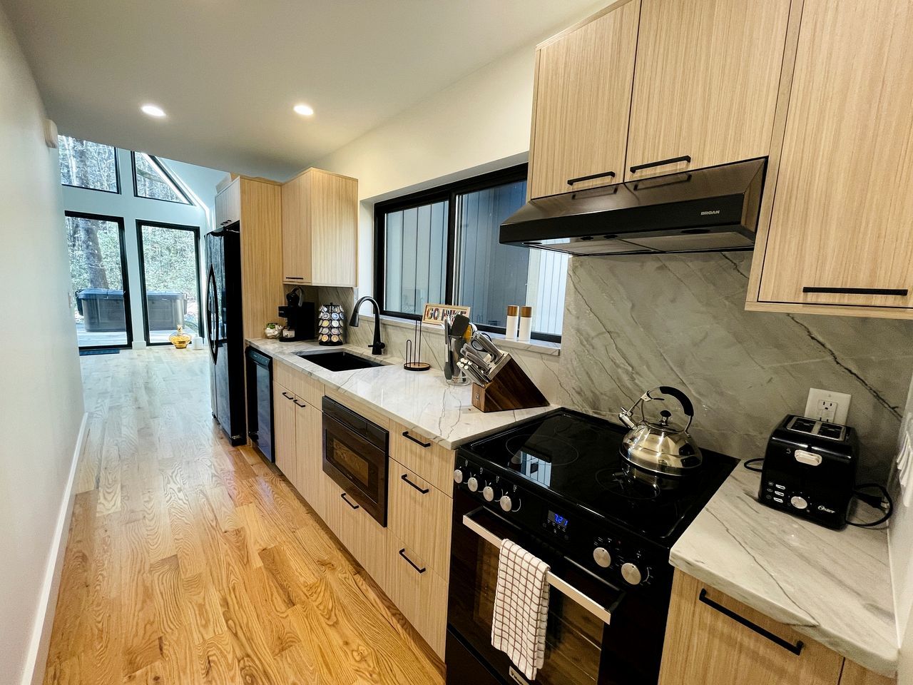 A modern kitchen with a central island, double sink, and a stove.