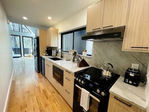 Una cocina moderna con una isla central, pileta doble y estufa.