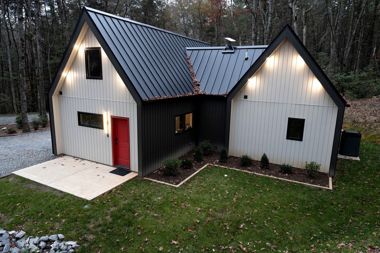 A two-story building with a red door, a metal roof, and a small porch area.