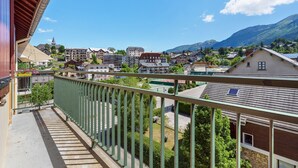 A balcony with a view of a town, buildings, and mountains.