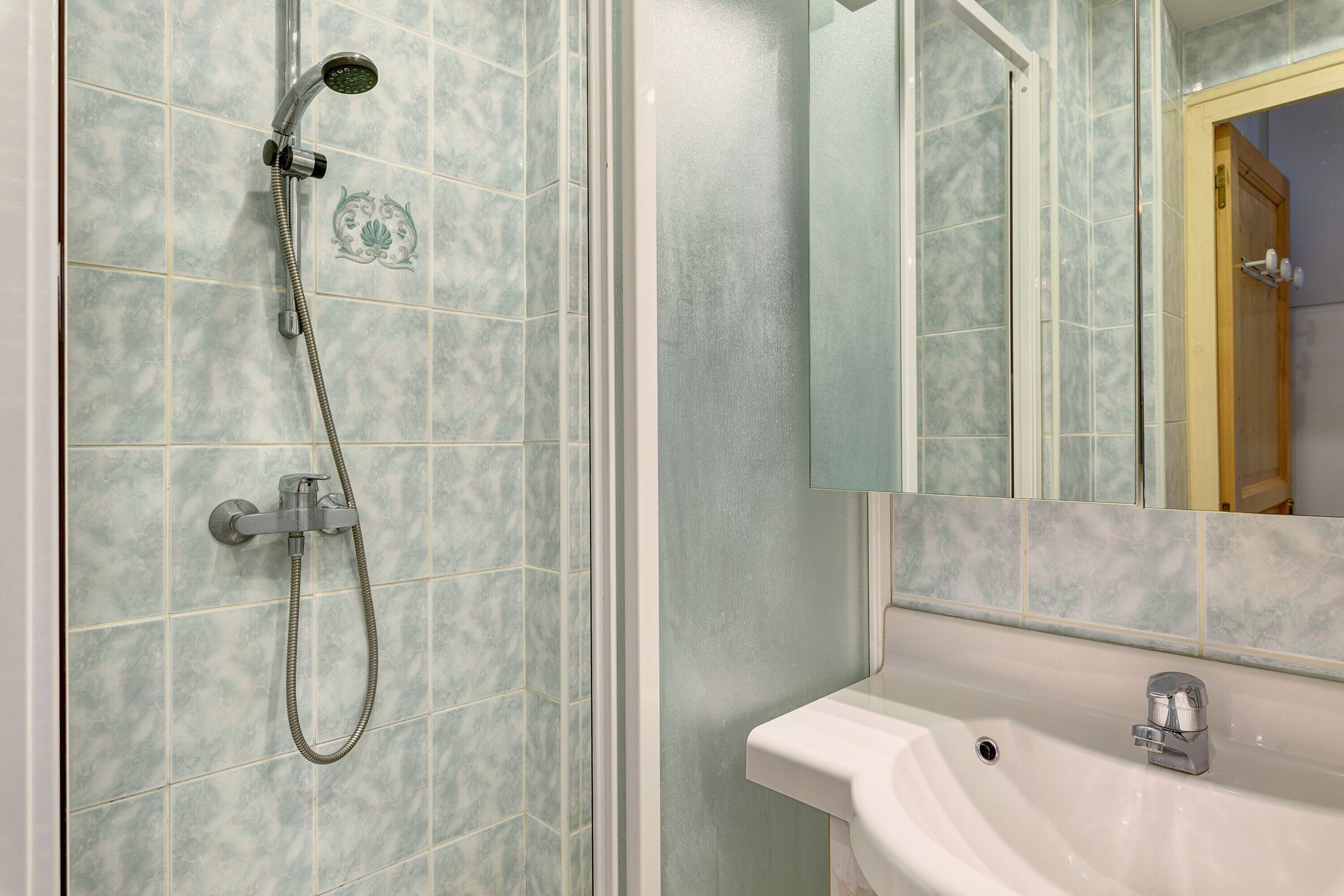 A bathroom with a shower, sink, and mirror.