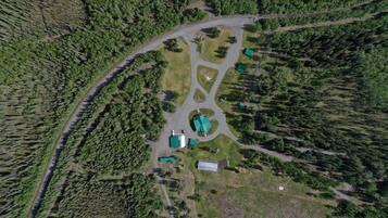 An aerial view of a property with a central building surrounded by forested areas and a winding road.