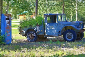 A vintage USAF vehicle with a blue cab parked beside a rusted blue utility box in a grassy area with trees in the background. - Secluded Rustic Wilderness Lodge & Cabin Retreat with Private Lake, Sauna & Adventure Trails near Tok, Alaska (Tok)