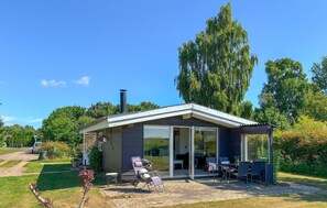 Ein modernes Haus mit Terrasse, Sitzgelegenheiten im Freien und einem Schornstein.