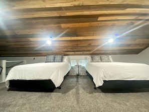 A room with two beds, a small table, and a window with blinds. - Creek Cabin ADA accessible in Livingston, Texas (Livingston)