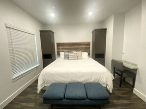 A bedroom with a bed, bench, desk, and window. - Creek Cabin ADA accessible in Livingston, Texas (Livingston)