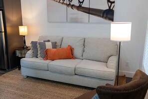 En stue med en grå sofa, en brun lænestol, et lille sofabord og en gulvlampe.