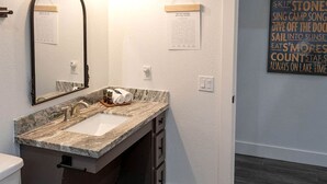 A bathroom with a marble sink, a mirror, a towel rack, and a wall with motivational quotes. - Creek Cabin ADA accessible in Livingston, Texas (Livingston)