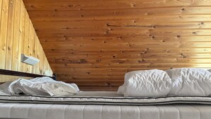 Una cama individual con ropa de cama blanca en una habitación con paneles de madera en el techo.