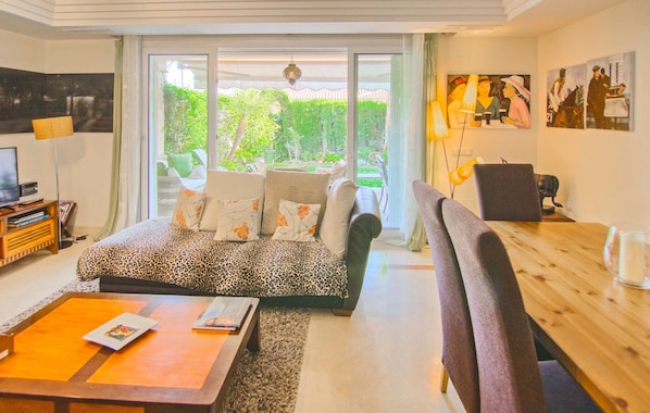 A living room with a sofa, a coffee table, a TV, and a dining area with chairs and a table. - Awesome home in Mijas with swimming pool (Mijas)