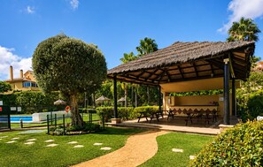 A covered outdoor seating area with picnic tables, a swimming pool, and a well-maintained garden. - Awesome home in Mijas with swimming pool (Mijas)