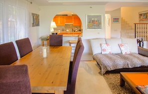A living room with a wooden dining table, purple chairs, a sofa with patterned cushions, and a kitchen visible through an archway. - Awesome home in Mijas with swimming pool (Mijas)