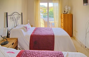 A bedroom with a bed, a bedside table, a dresser, and a window with a view of a balcony. - Awesome home in Mijas with swimming pool (Mijas)