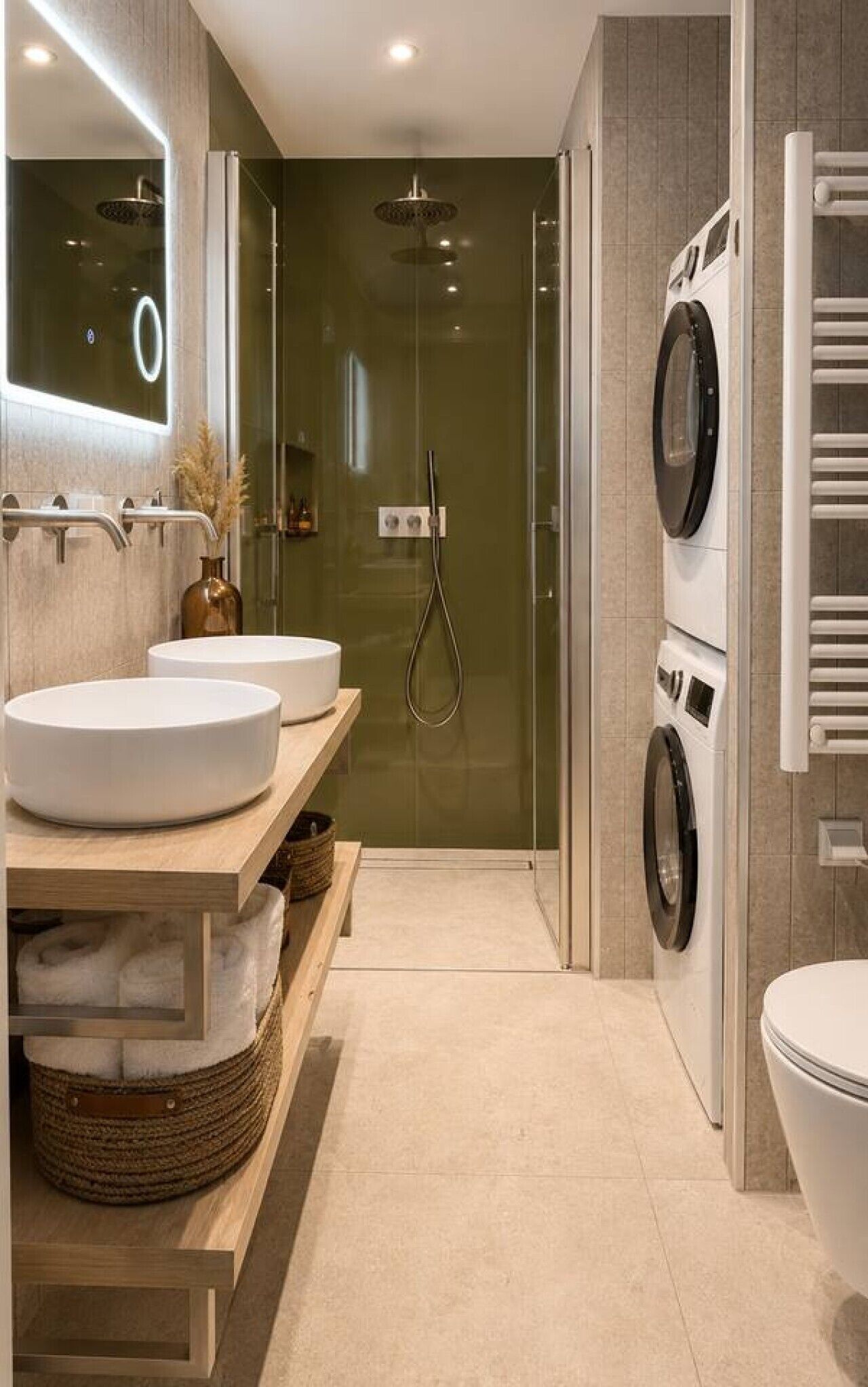 Een moderne badkamer met twee wastafels, een douche, een wasmachine en een toilet.