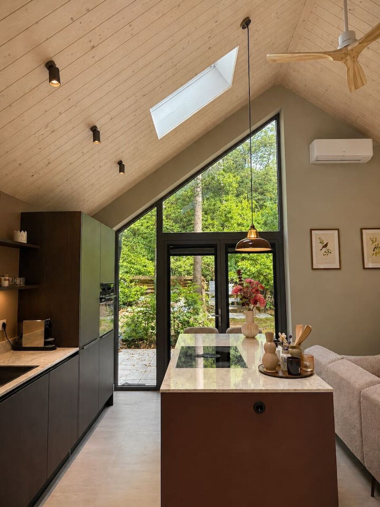 A modern kitchen with a skylight, large windows, and a central island.