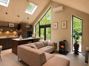 Una sala de estar moderna con un sofá, una chimenea y ventanas amplias.