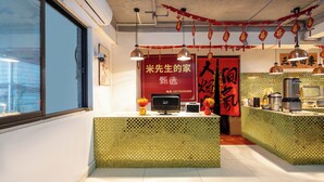 Interior de restaurante com balcão azulejado, decorações pendentes e uma faixa vermelha com caracteres chineses.
