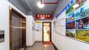 Corredor com elevador, uma placa vermelha e parede com fotografias.