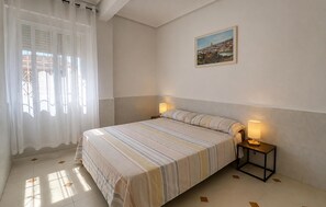 Ein Hotelzimmer mit einem Bett, zwei Nachttischlampen, einem Bild an der Wand und einem Fenster mit Vorhängen.