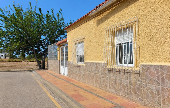 A building with a yellow stucco exterior, stone base, and red-tiled roof.