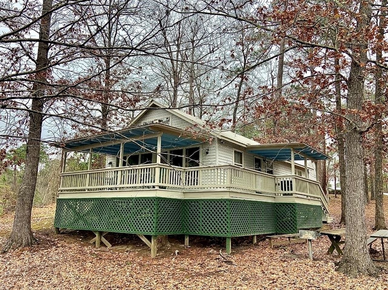 A two-story house with a balcony, surrounded by trees.