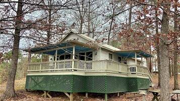 A two-story house with a balcony, surrounded by trees.
