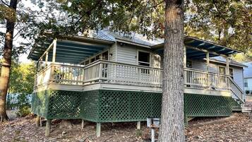 A two-story house with a balcony, a covered porch, and a tree in front.
