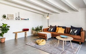 A modern living room with a brown leather sofa, a round coffee table, a patterned rug, a wooden bench, and a hanging light fixture. - Gorgeous home in Artà with private swimming pool, can be inside or outside (Artà)