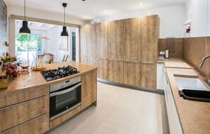 Eine moderne Küche mit Holzschränken, einem Gasherd und einem Spülbecken.