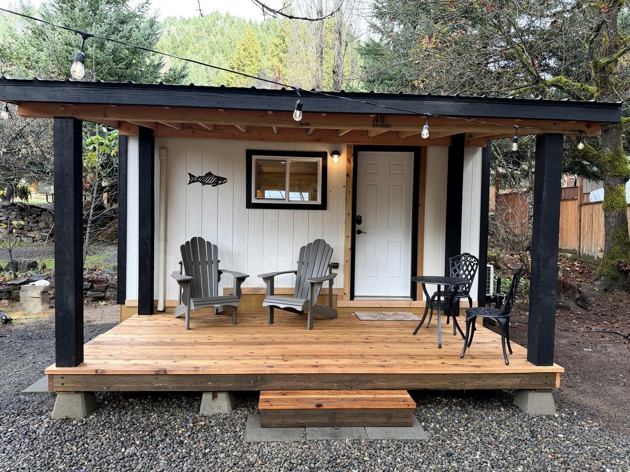 Eine Holzterrasse mit Adirondack-Stühlen, einem Tisch und einer Bank.