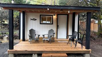 Eine Holzterrasse mit Adirondack-Stühlen, einem Tisch und einer Bank.