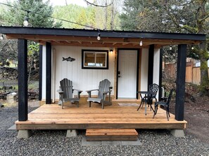 Eine Holzterrasse mit Adirondack-Stühlen, einem Tisch und einer Bank.