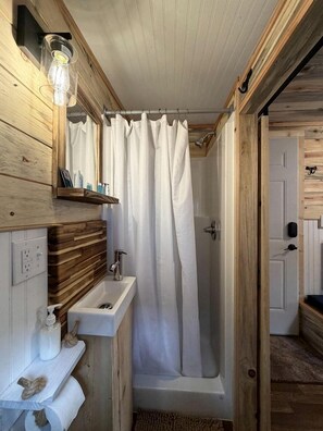 A wooden interior with a shower, a sink, and a light fixture. - Cute Cozy Cabin for Two for a Romantic Escape in the Umpqua National Forest in Oregon (Idleyld Park)