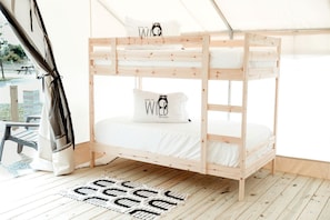 Un lit superposé avec un matelas blanc et deux oreillers, dont l’un est orné d’un motif représentant un ours.