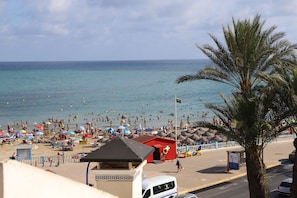 Ein Strand mit Sonnenschirmen, einem Rettungsturm und einem roten Gebäude.